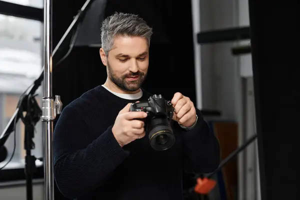 A focused person adjusts camera settings, readying for a shoot in the dim studio light. — Stock Photo