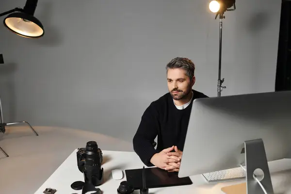 A man dedicated to capturing moments sits thoughtfully at his workspace, surrounded by equipment. — Stock Photo
