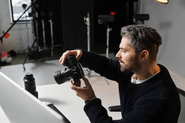 A focused man examines his camera settings before starting a creative session in a modern studio. — Stock Photo