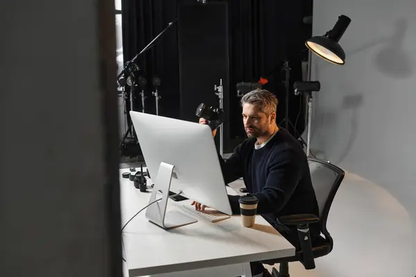 A skilled worker focuses on editing digital content while enjoying a warm beverage at his desk. — Stock Photo