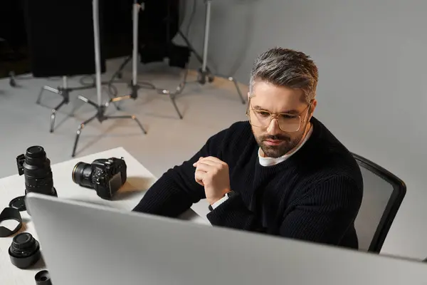 A man is focused on editing photos in a modern setup during the day. — Stock Photo
