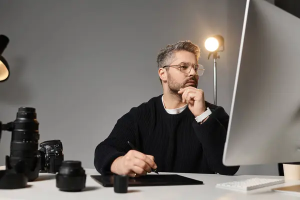 A dedicated man edits creative content at his desk using various tools. — Stock Photo