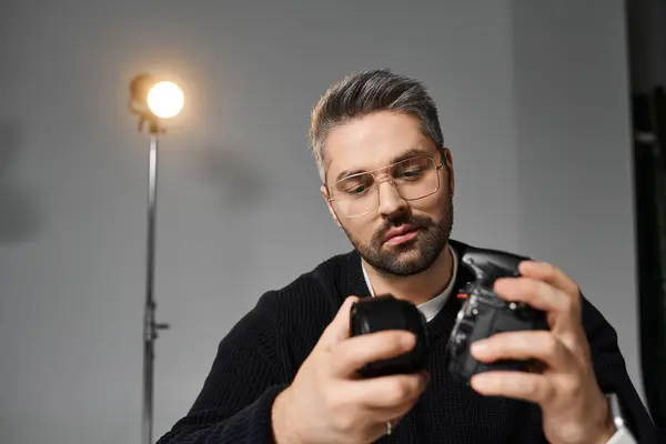 A man inspects his camera gear in a bright studio, highlighting his dedication. — Stock Photo