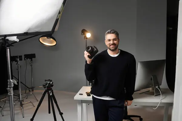 Una persona segura con una cámara está lista en medio de un equipo de estudio para capturar arte. - foto de stock
