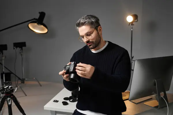 A man examines his camera in a stylish studio, surrounded by professional equipment and lighting. — Stock Photo