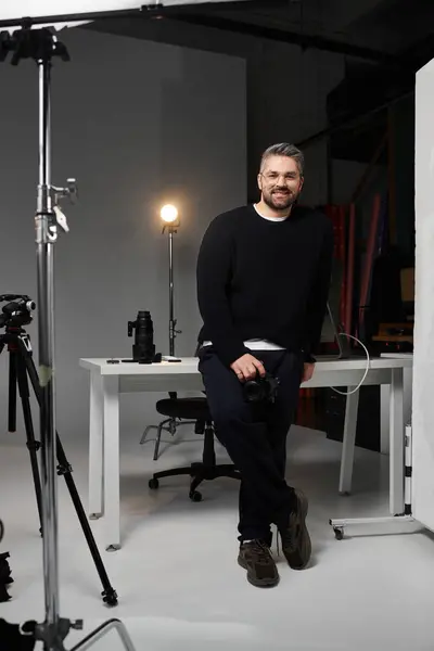 Professional with a camera stands confidently in a contemporary studio space filled with equipment — Stock Photo