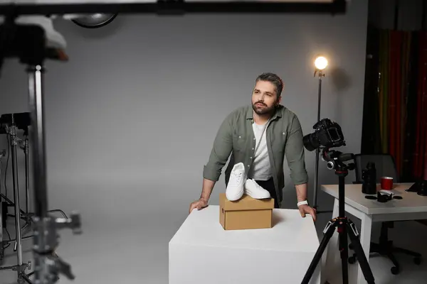A man works diligently in a studio, showcasing a stylish shoe creatively positioned on a box. — Stock Photo