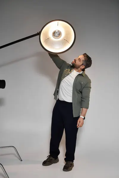 Un artiste dévoué affine la configuration de l'éclairage pour capturer des clichés parfaits dans un cadre de studio. — Photo de stock