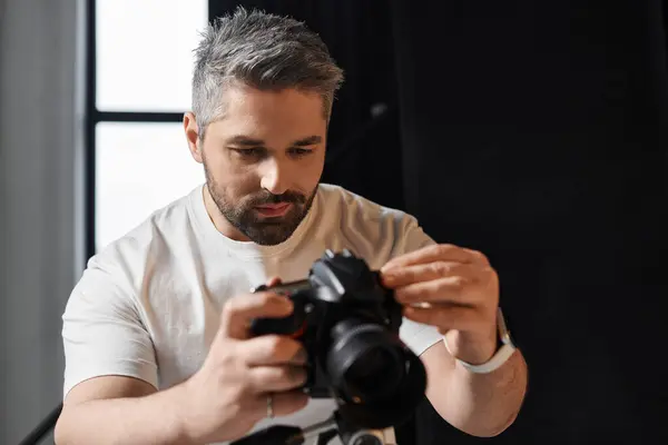 A focused photographer adjusts camera settings in a bright studio, ready to capture stunning images. — Stock Photo