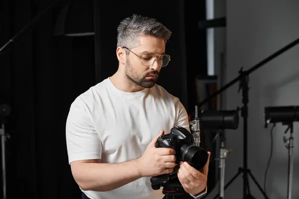 Un uomo finemente sintonizza la sua macchina fotografica al chiuso, completamente dedicato al suo mestiere. — Foto stock