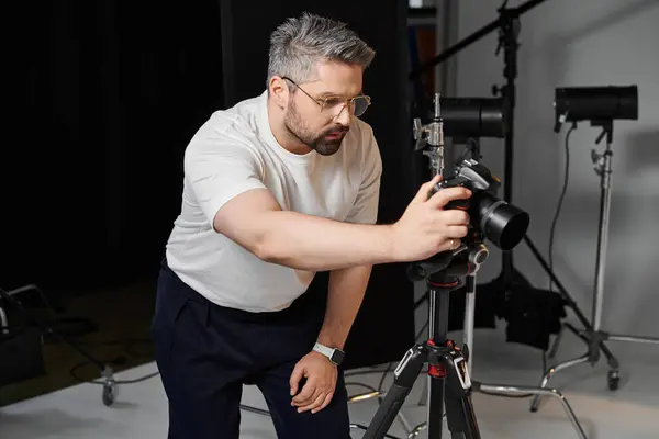 A dedicated man sets up his camera on a tripod to capture stunning studio shots. — Stock Photo