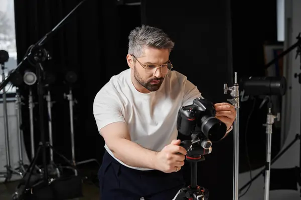 Мужчина прекрасно настраивает свои фотоаппараты в профессиональной фотостудии. — стоковое фото