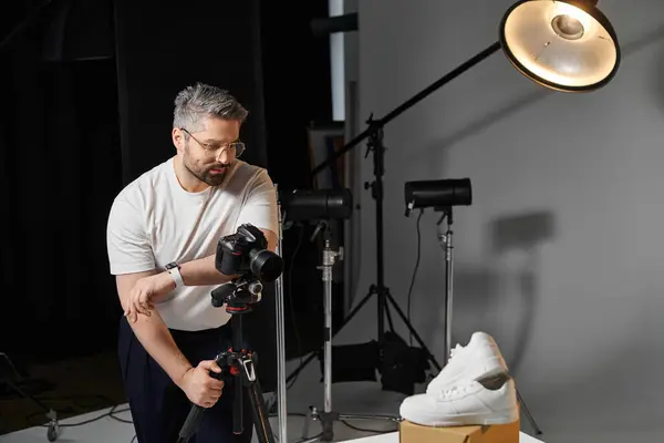 A man sets up his camera to shoot a stylish sneaker in a well lit studio. — Stock Photo