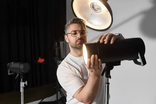 Un uomo dedicato perfeziona l'illuminazione mentre si prepara per un progetto creativo in uno studio. — Foto stock