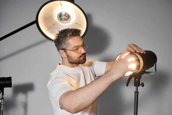 A man skillfully adjusts studio lighting equipment while preparing for a creative shoot. — Stock Photo