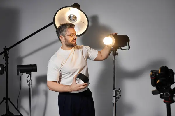 L'homme installe un équipement d'éclairage dans un studio bien équipé, se préparant à une séance de photographie. — Photo de stock