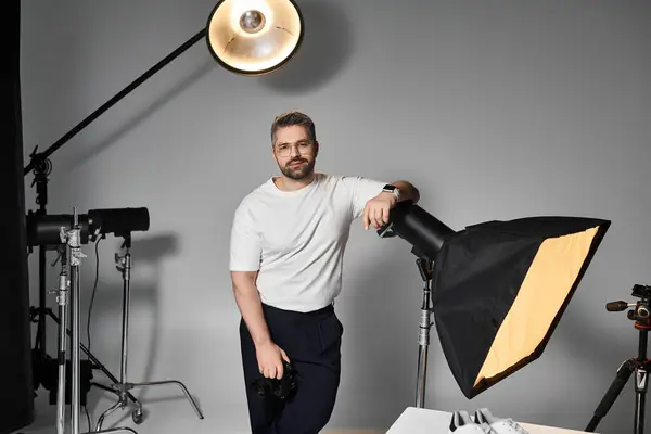 Un individuo talentoso se encuentra confiado en un estudio, listo para capturar imágenes sorprendentes con habilidad. - foto de stock