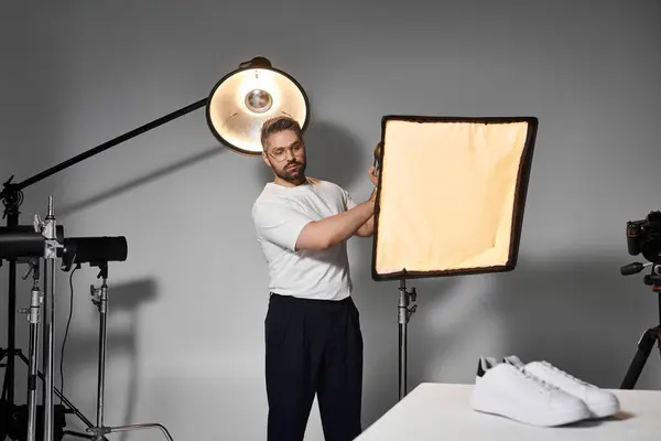 A pro sets up softbox lighting to creatively capture footwear in a studio. — Stock Photo