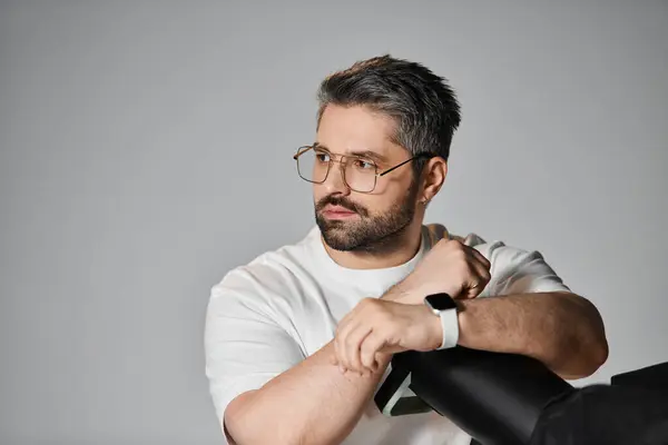 A man in casual attire engages thoughtfully in his work within a modern, minimalist studio. — Stock Photo