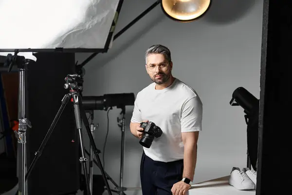 A man stands confidently in a studio, ready to capture stunning visuals with his camera. — стоковое фото