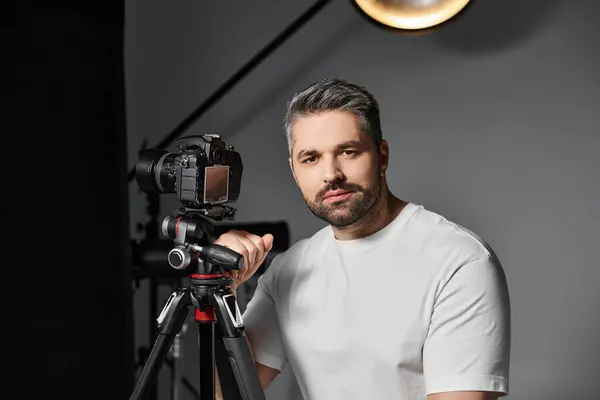 A man confidently poses beside his camera setup, ready for a creative endeavor in photography. — Stock Photo