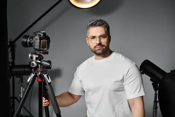 Кваліфікований фотограф впевнено позує зі своєю камерою у яскравій студії, готова до зйомок. — стокове фото