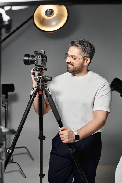 A skilled man is adjusting his camera equipment while preparing for a studio session. — Stock Photo