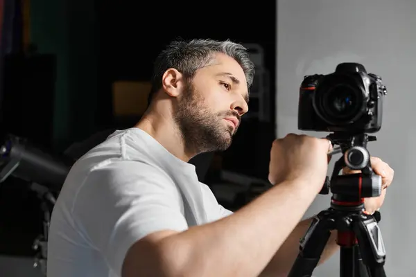 A professional captures an artistic moment, meticulously fine tuning his camera in a creative space. — Stock Photo