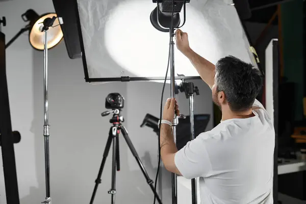 Un experto individuo afina el equipo de iluminación, preparándose para una sesión cautivadora. — Stock Photo