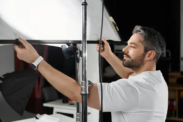 Un individuo enfocado ajusta la configuración de la iluminación mientras se prepara para un proyecto creativo en un estudio. - foto de stock