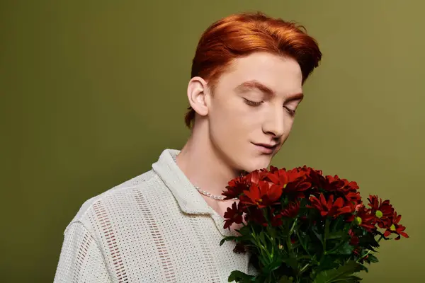 A young man gently holds bright flowers, conveying deep emotions of affection. — Stock Photo