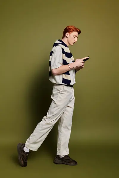 Handsome man casually dressed, reading intently by a vibrant green wall. — Stock Photo