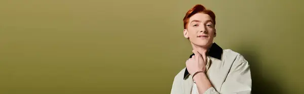 A young, handsome man displays genuine emotion and style against a simple green backdrop. — Stock Photo