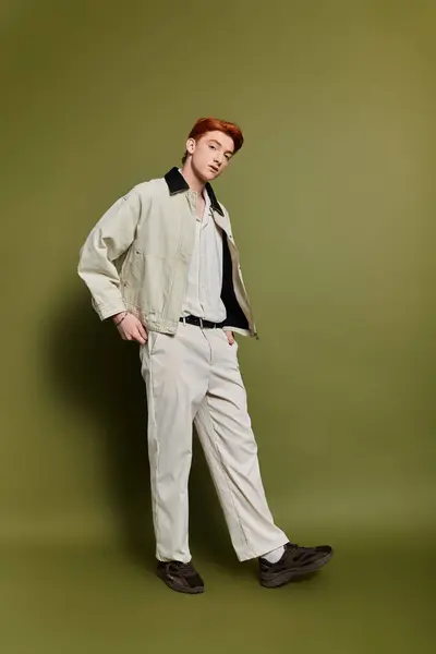 A young man shows emotion in a trendy outfit against a soft green backdrop. — Stock Photo