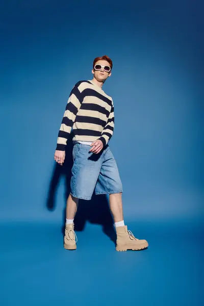 A young and handsome man wearing a striped sweater and shorts showcases emotion in fashion. — Stock Photo