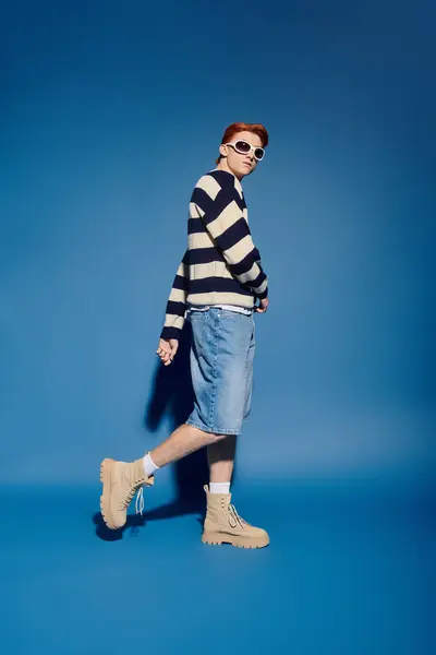 A young man confidently poses in stylish attire, showcasing deep emotions against blue. — Stock Photo