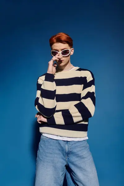 A young man with stylish striped attire and sunglasses poses with a thoughtful expression. — Stock Photo