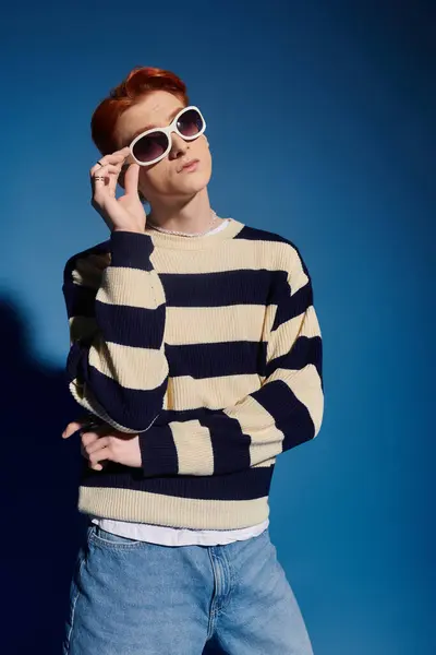Ein junger Mann zeigt starke Emotionen und posiert selbstbewusst mit stylischer Sonnenbrille und gestreiftem Pullover. — Stockfoto