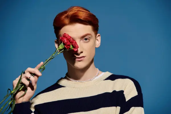 A handsome young man with vibrant red hair gently holds a rose, expressing deep emotions. — Stock Photo