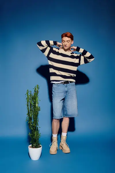 Un jeune homme aux traits saisissants se déplace près d'une plante en pot, perdu dans la pensée profonde. — Stock Photo