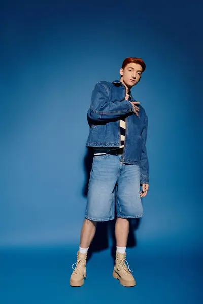 A young man in denim expresses emotion and style against a bright blue backdrop. — Stock Photo