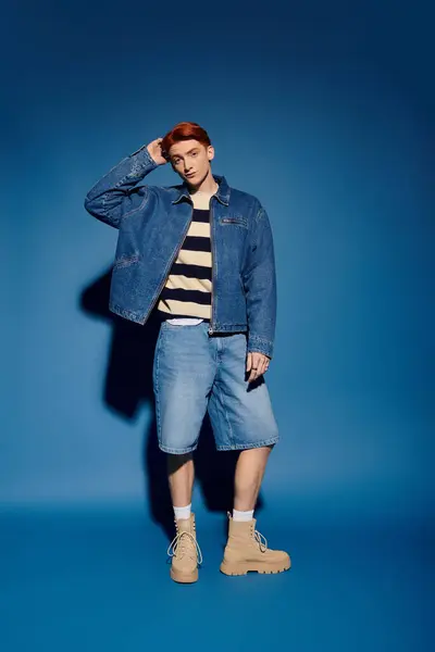 Young man showcases trendy attire while embodying emotion and confidence in a striking blue setting. — Stock Photo