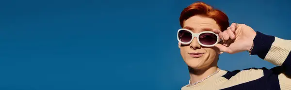 A young, handsome man with red hair strikes a playful pose while enjoying a sunny day outdoors. — Stock Photo