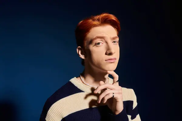 A handsome young man with vibrant red hair contemplates thoughtfully against a deep blue backdrop. — Stock Photo