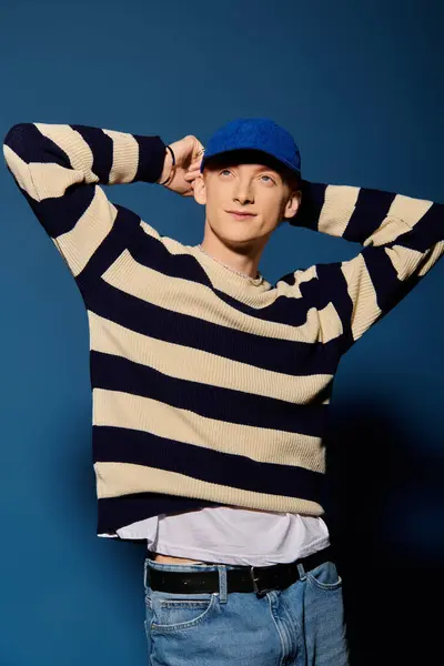 Ein gutaussehender junger Mann nimmt eine nachdenkliche Pose ein und trägt einen gestreiften Pullover und eine Mütze. — Stockfoto