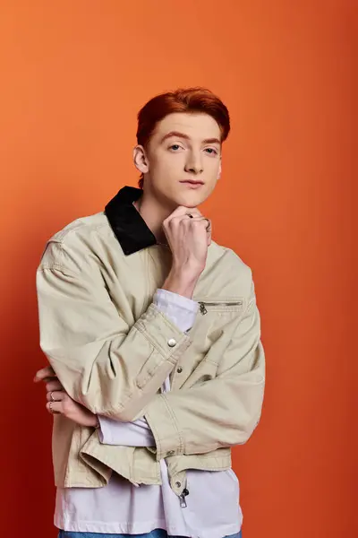 Красивый молодой человек задумчиво позирует на ярком оранжевом фоне.. — стоковое фото