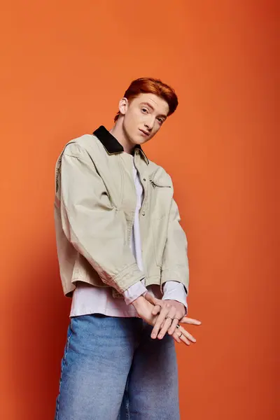 Stylish young man in a studio with orange walls reveals his emotional depth. — Stock Photo