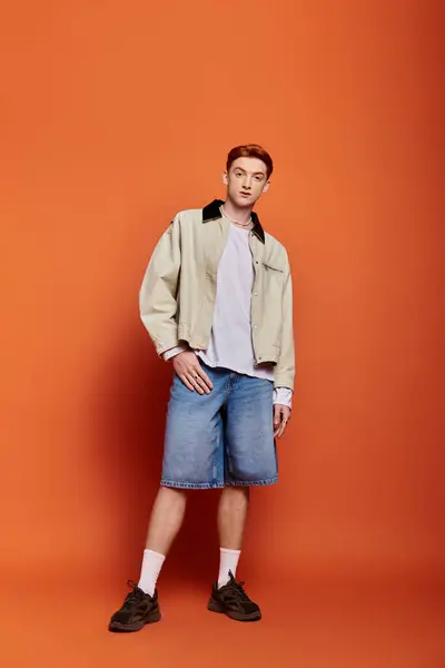 A handsome young man stands with poise, showcasing his stylish outfit in a warm setting. — Stock Photo