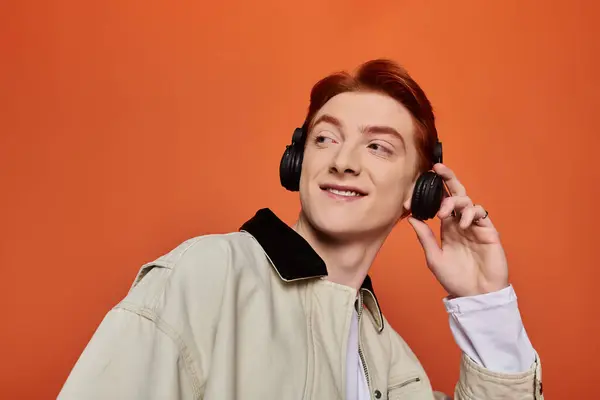 A young and handsome man with red hair listens to music intently, showing his joy and emotion. — Stock Photo