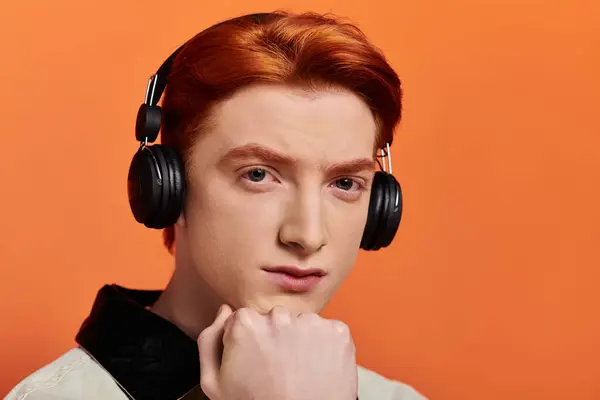 A young handsome man with red hair is deeply immersed in music, showing emotion while listening. — Stock Photo